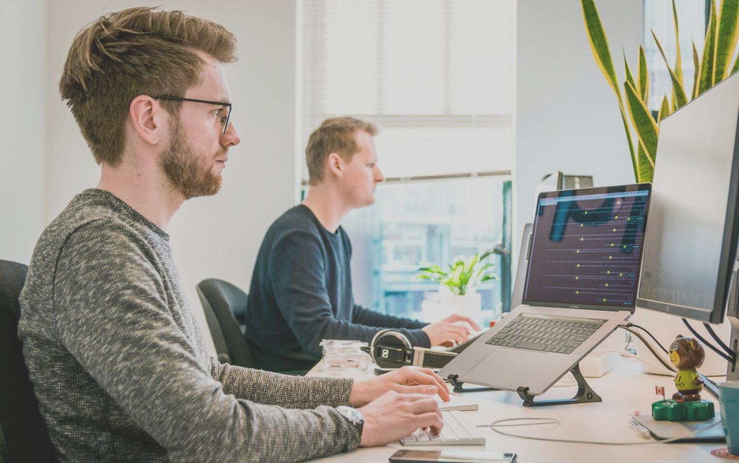 Teamarbeit bei der Marktanalyse mit mehreren Bildschirmen und Datenvisualisierungen